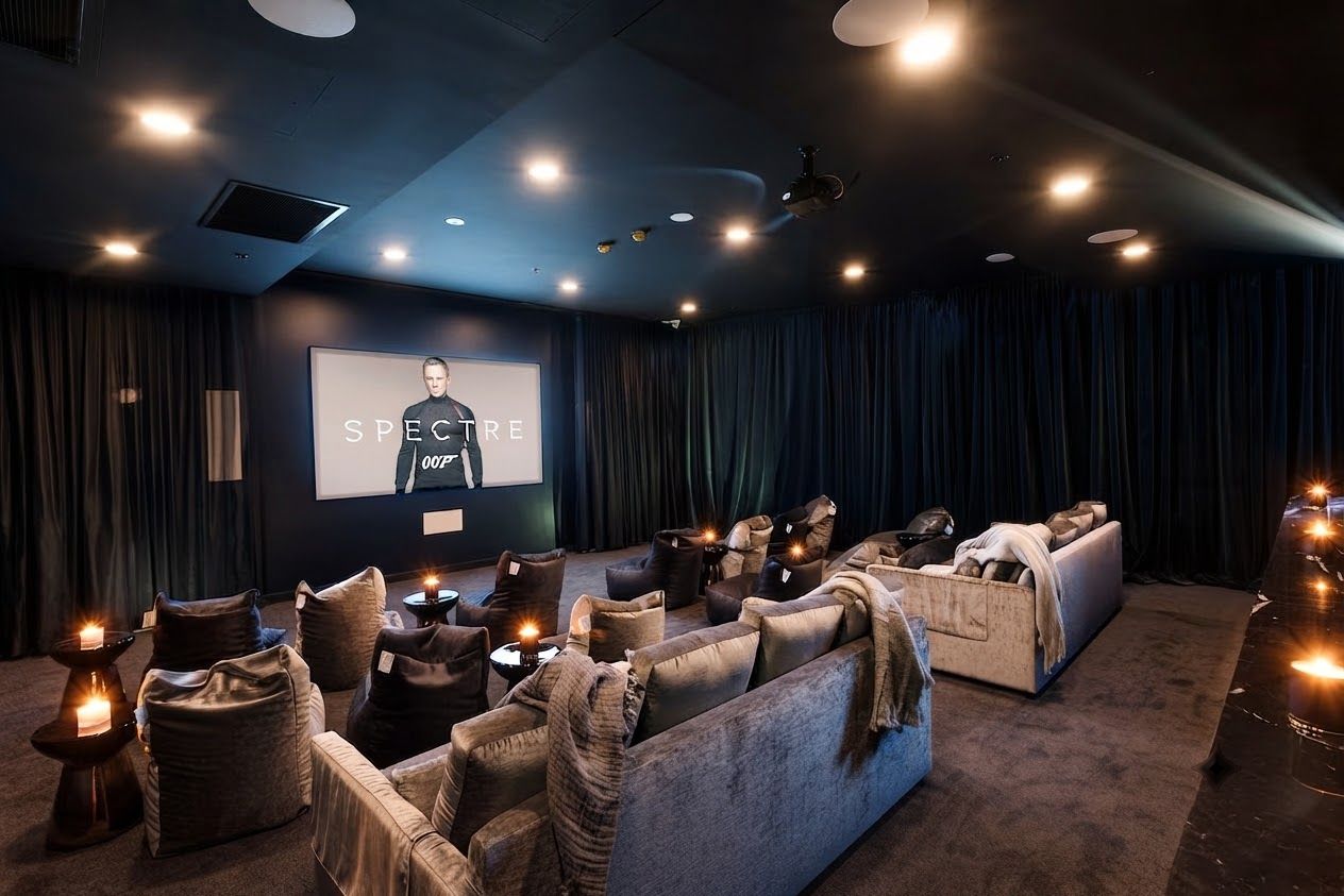 A home theater with a large screen, multiple seating areas, and ambient lighting.