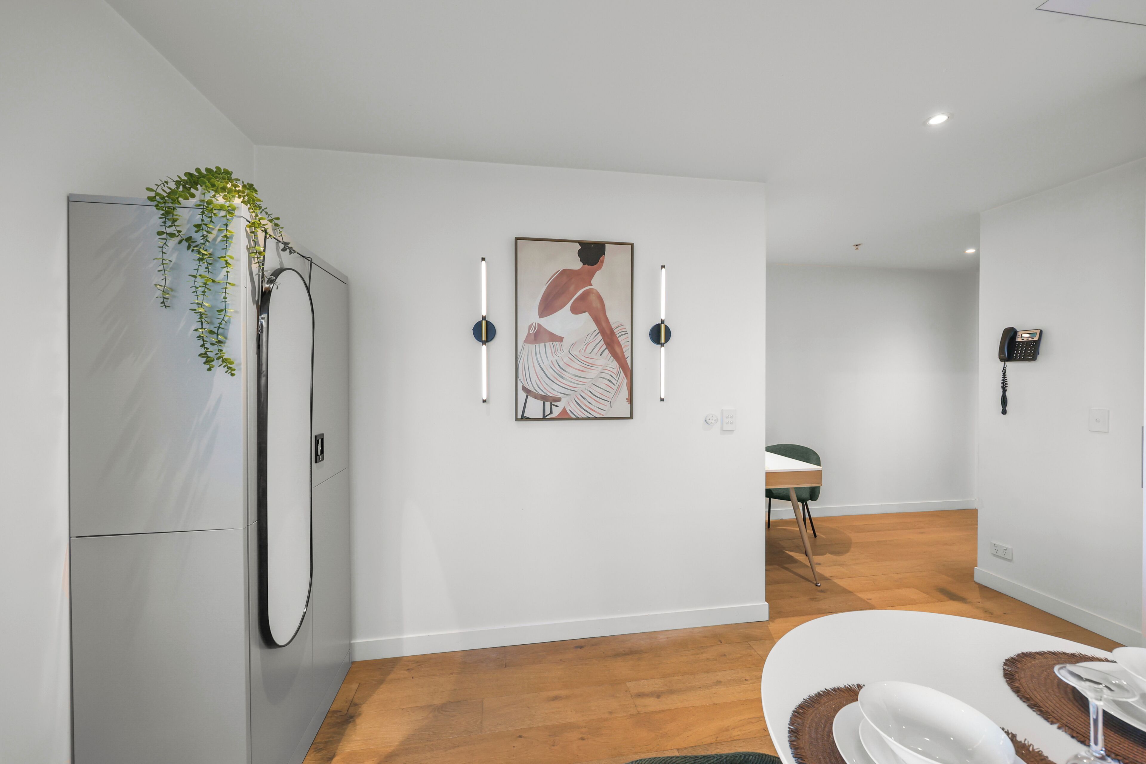 A modern kitchen with a refrigerator, a dining area with a table and chairs, and a wall-mounted phone.