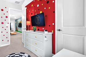 A hallway with a red wall featuring a logo, a white console with drawers, and a television mounted above it. - 5BR Private Pool | Windsor Island Resort (Davenport)