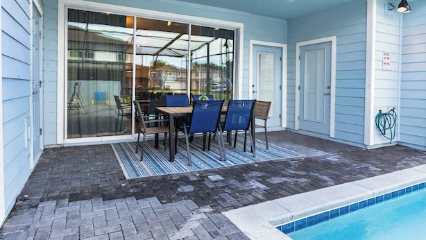 Ein überdachter Patio-Bereich mit Pool, Tisch und Stühlen sowie einem Schlauch zur Poolpflege.