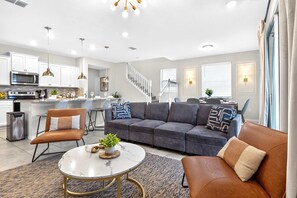 Un salon moderne avec un canapé gris, un fauteuil en cuir marron et une table basse blanche.