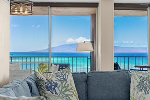 Ein Balkon mit Blick auf das Meer und ein Berg, ausgestattet mit einer Couch und einer Lampe.