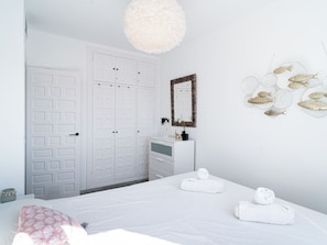A bedroom with a bed, a dresser, a mirror, and a wall with decorative fish. - Apartment  by Interhome (Nerja)
