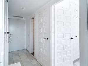 A hallway with white doors, a tiled floor, and a ceiling light. - Apartment  by Interhome (Nerja)