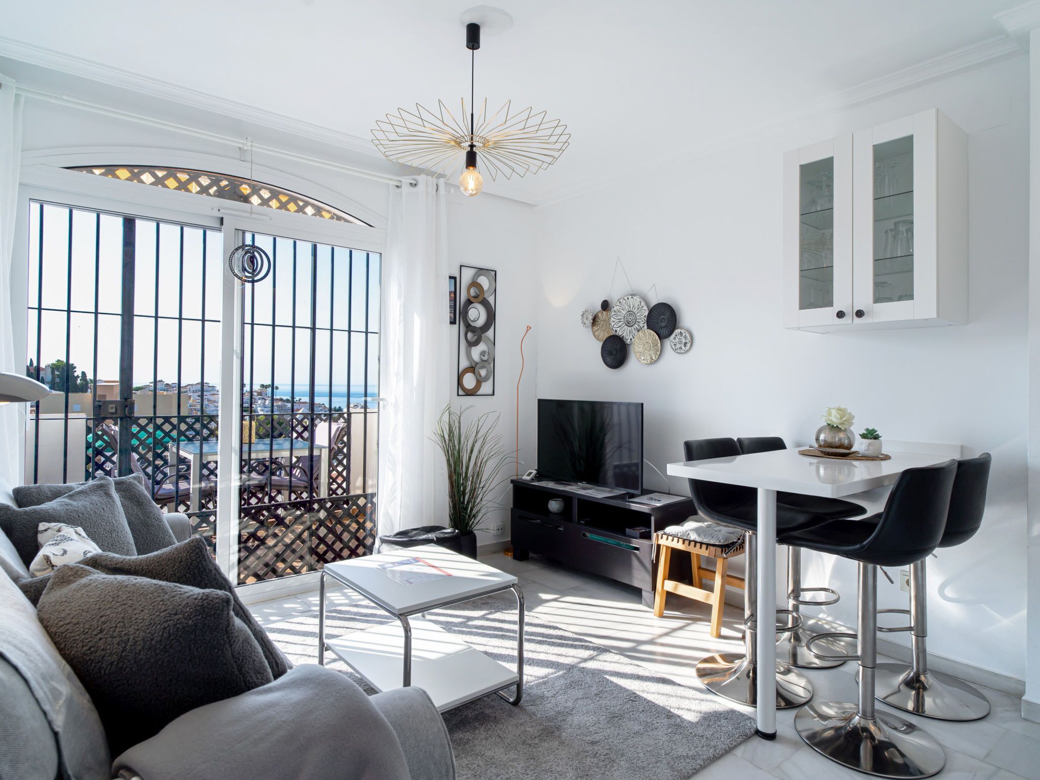Un salon moderne comprenant un canapé, un téléviseur, un coin repas et un balcon avec vue.