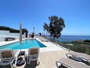 Ein Poolbereich mit Liegestühlen und Meerblick.