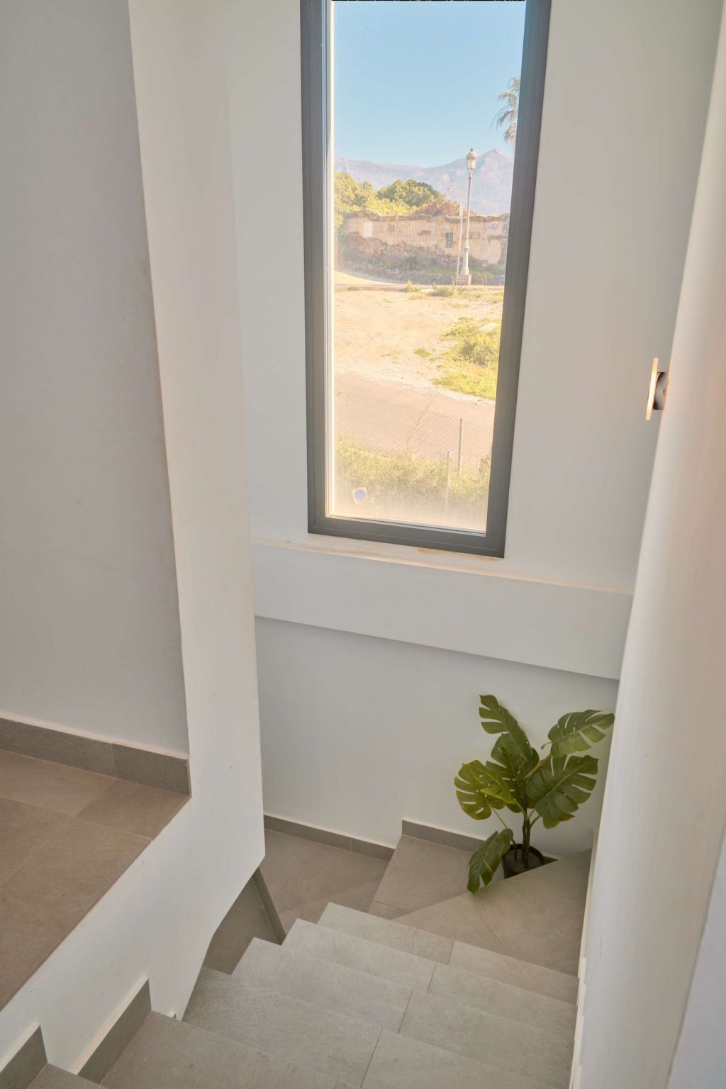 A staircase leading to a window with a view of a landscape.