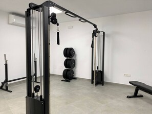 Ein Fitnessraum mit Krafttrainingsgeräten, darunter ein Squat-Gestell und eine Hantelbank.
