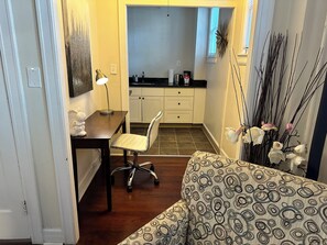 A compact living space with a kitchenette, a dining area with a table and chair, and a patterned sofa.