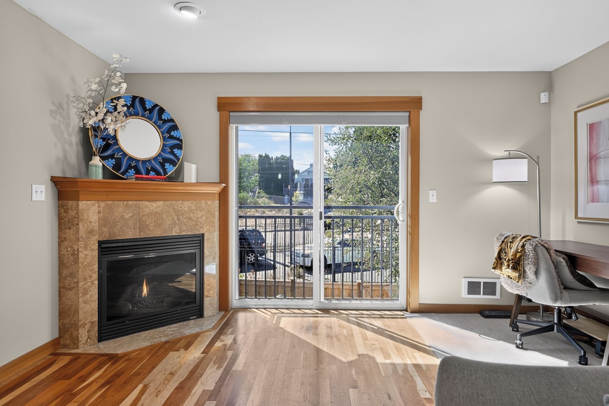 A living room with a fireplace, a large window with a view of the outdoors, and a modern chair.