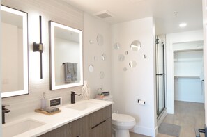 Un baño moderno con dos lavamanos, inodoro y zona de ducha.