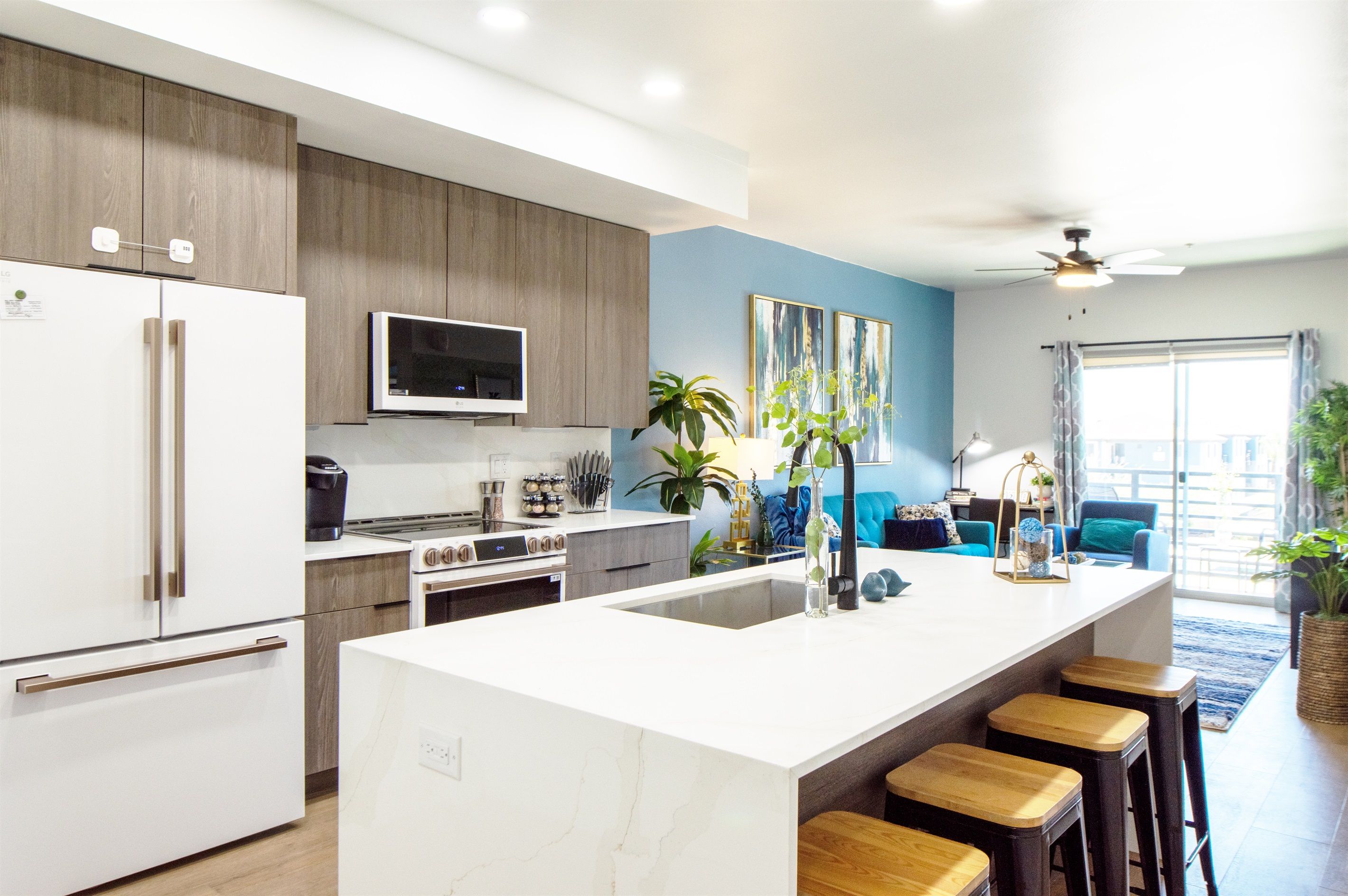 Una cocina moderna con una isla grande, taburetes de bar y una zona de comedor con sillas azules.