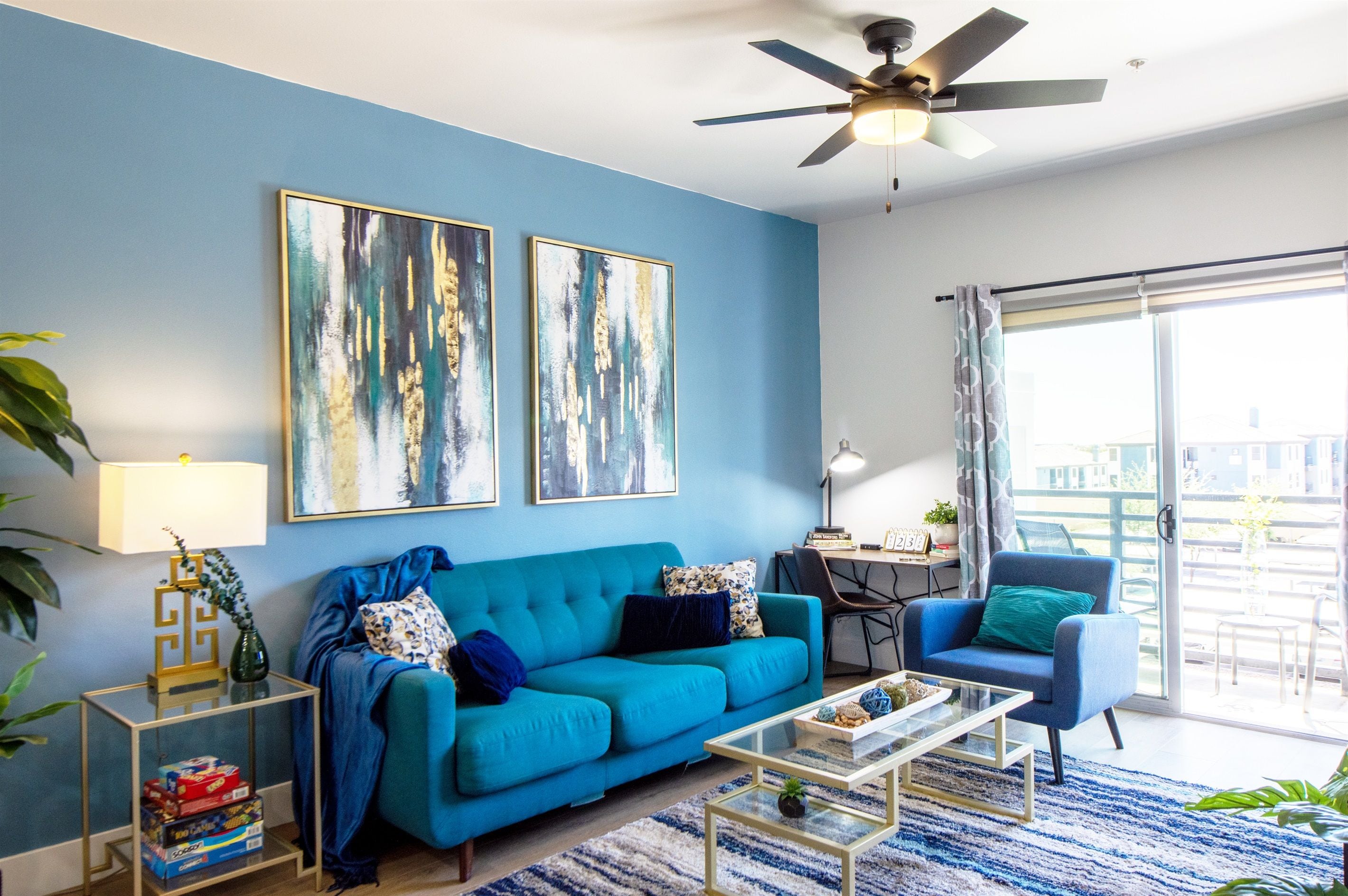 A living room with a blue sofa, a coffee table, and two paintings on the wall.