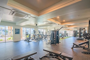 Ett gym med olika typer av träningsutrustning, stora fönster och utsikt över omgivningen.
