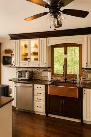 A kitchen with a built-in oven, microwave, and dishwasher, a large window, and a ceiling fan. - Lakefront 3-Bedroom Retreat on Huffman Lake (Elmira)