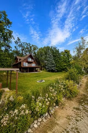 A wooden house with a well-maintained lawn and a clear sky. - Lakefront 3-Bedroom Retreat on Huffman Lake (Elmira)