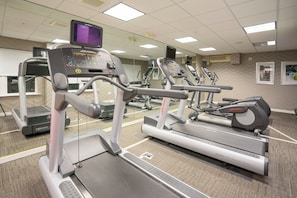 Ett gym med löpband, crosstrainers och en vägg täckt med speglar.
