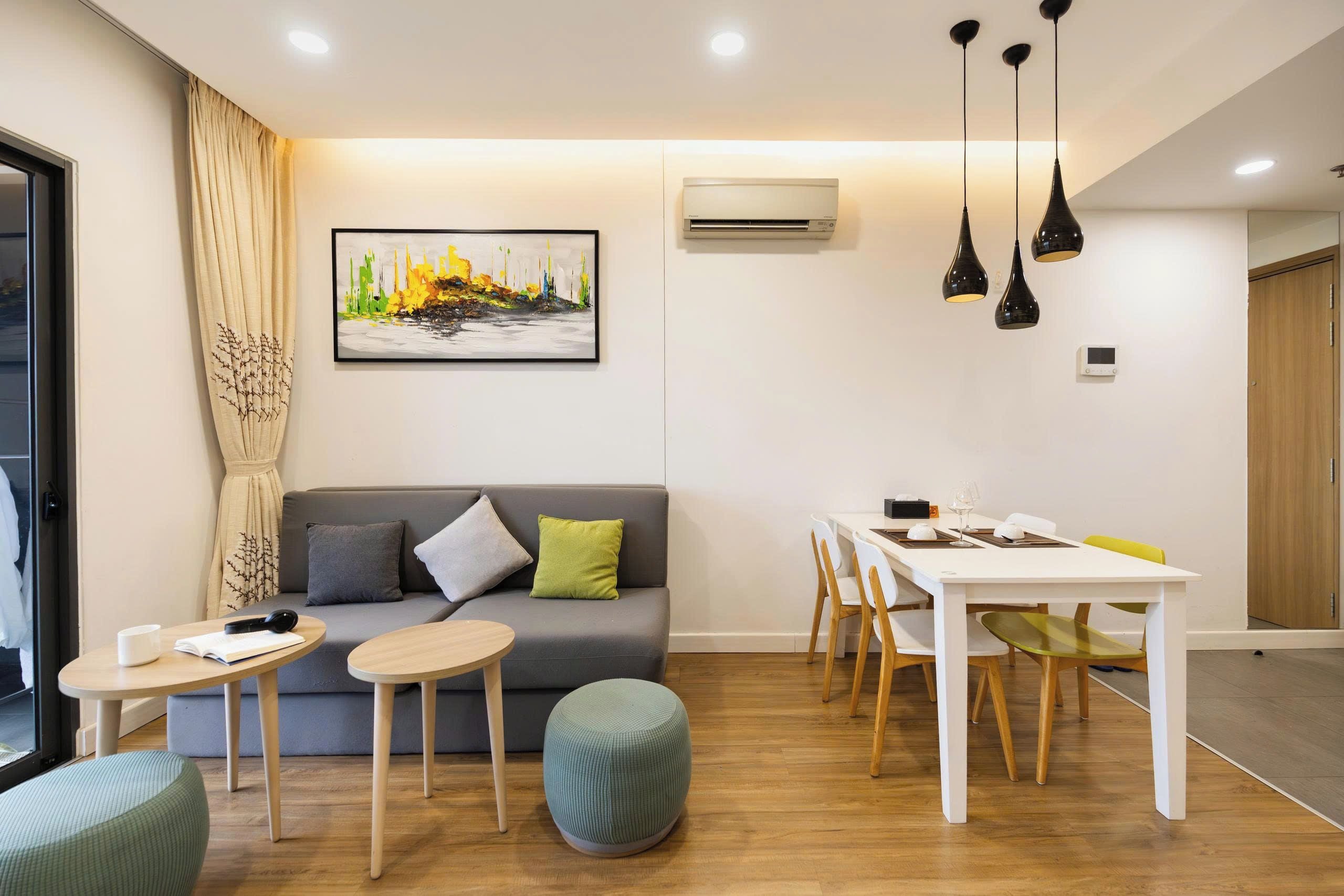 A modern living room with a sofa, a dining table, and a painting on the wall.