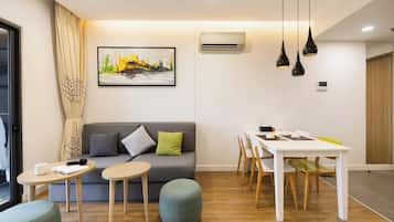 A modern living room with a sofa, a dining table, and a painting on the wall.