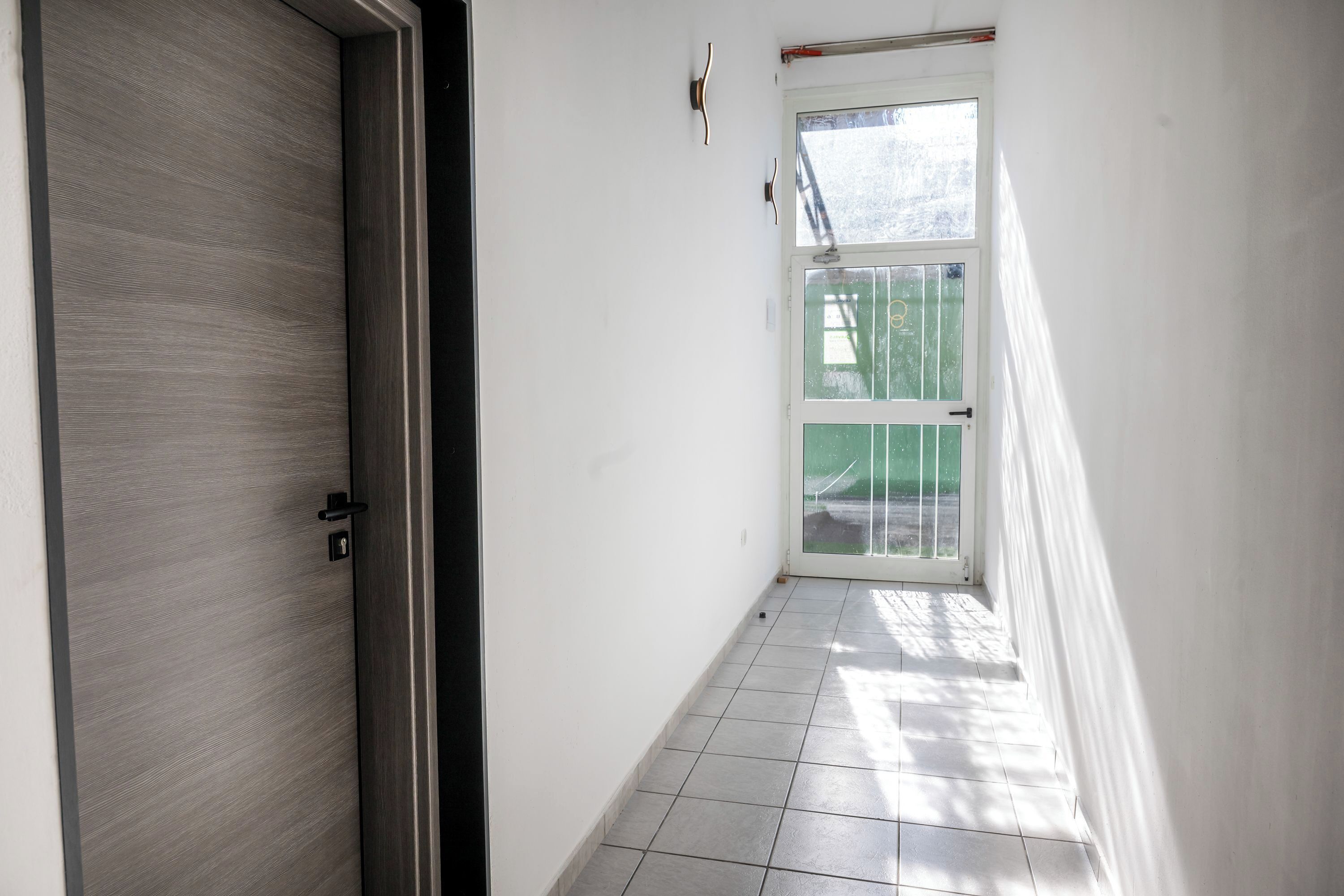 A narrow hallway with a door on the left and a window on the right.