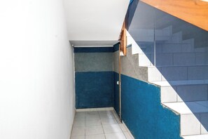Un couloir étroit avec un sol carrelé, un mur bleu et une porte en bois.