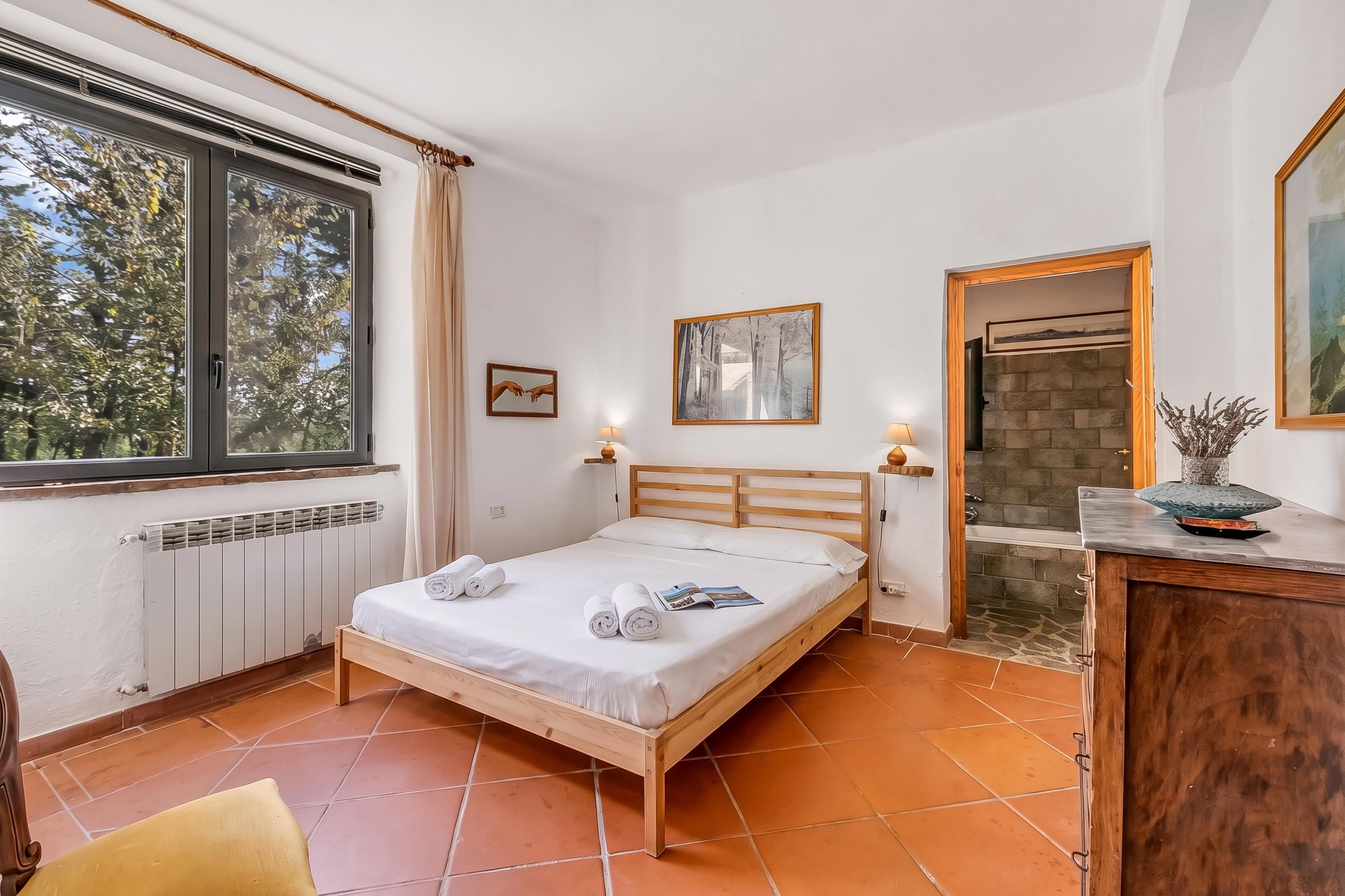 Ein Schlafzimmer mit einem hölzernen Bett, einem Fenster, einer Heizung und einem Kamin aus Stein.