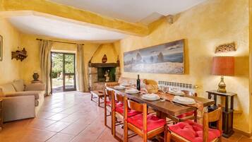 A dining area with a table set for four, a fireplace, and a painting on the wall.