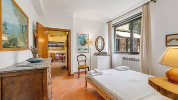 Un dormitorio con cama, escritorio, silla y ventana con cortinas.