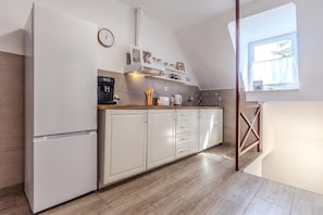 A modern kitchen with white cabinetry, a built-in oven, a coffee machine, and a window providing natural light. - Hunters Lodge 1 Lake Balaton, Badacsony Wine Region, Badacsonytomaj, Hungary (Badacsonytomaj)