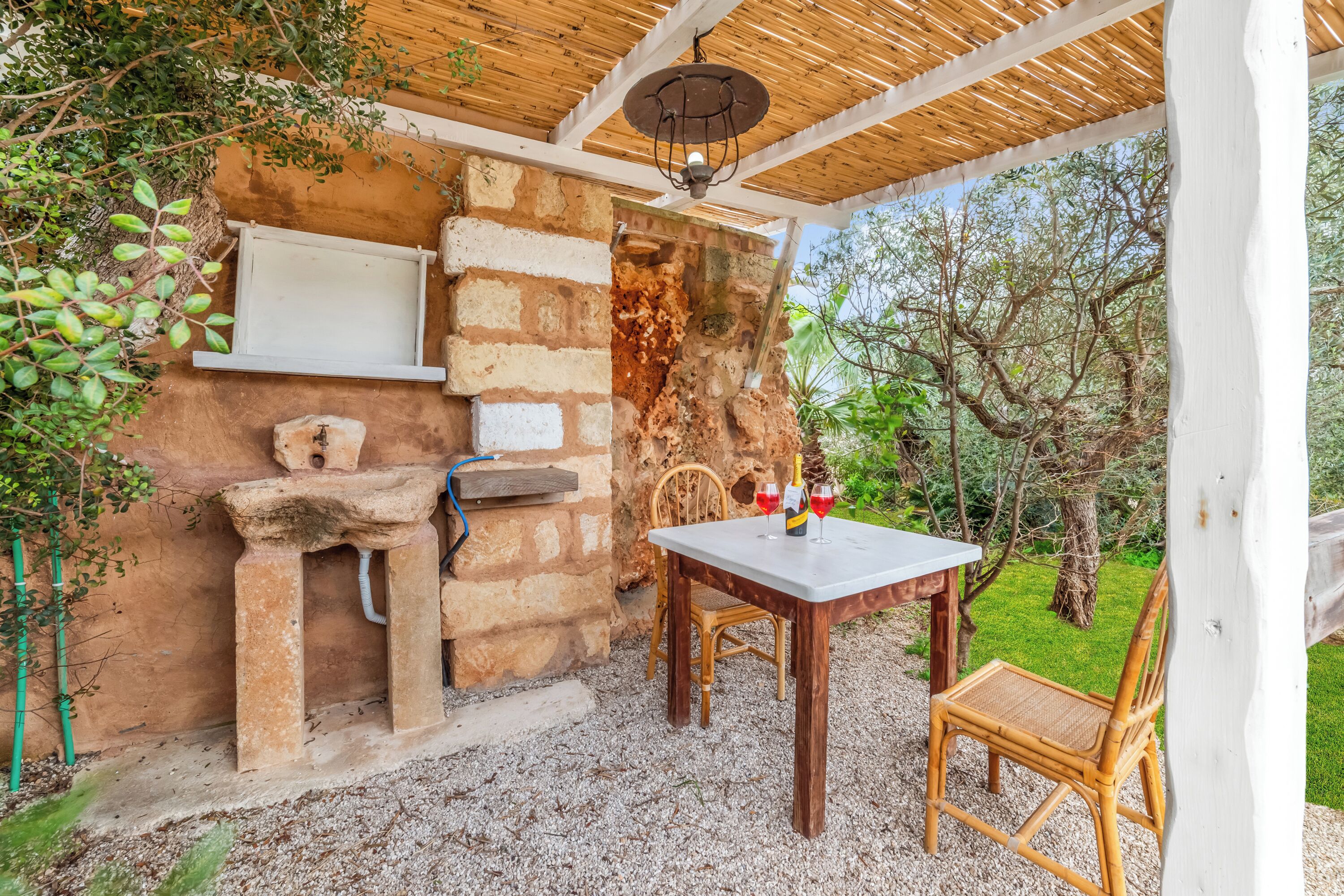 A rustic outdoor seating area with a stone wall, a wooden table, and a chair.