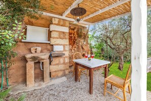 A rustic outdoor seating area with a stone wall, a wooden table, and a chair. - Villa Fontanelle Double Room 1, Ugento, Italy (Ugento)