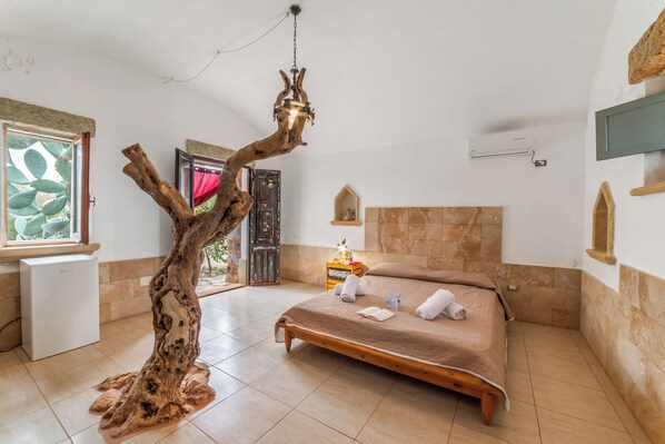 A bedroom with a wooden tree sculpture, a bed with towels, a small bedside table, and a window with a view. - Villa Fontanelle Double Room 1, Ugento, Italy (Ugento)