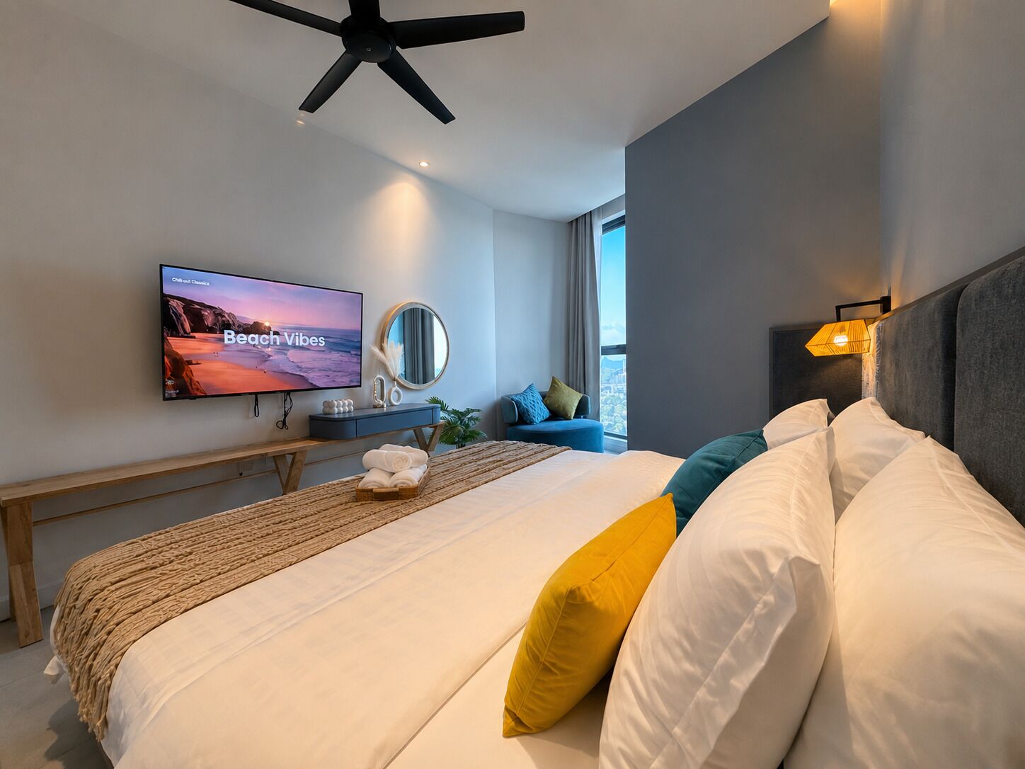 Quarto de hotel moderno com cama, televisão de tela plana, mesa de cabeceira, espelho e janela com vista.