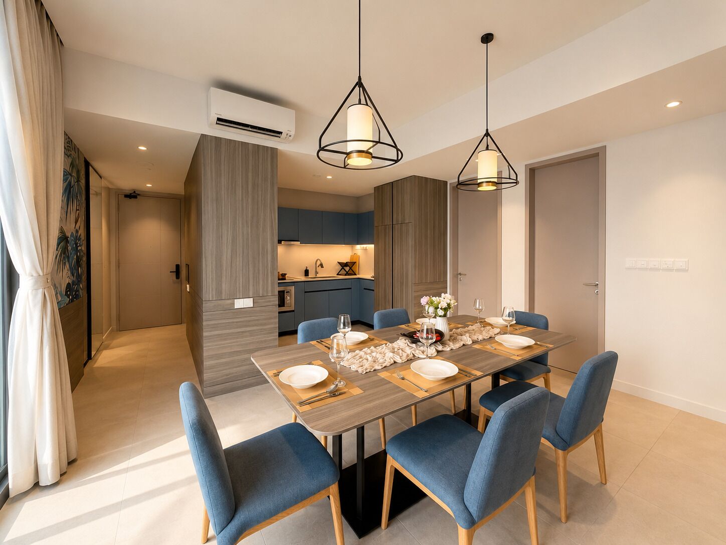 A modern dining area with a rectangular table set for four, blue upholstered chairs, and pendant lighting.