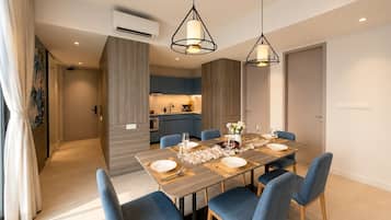 A modern dining area with a rectangular table set for four, blue upholstered chairs, and pendant lighting.