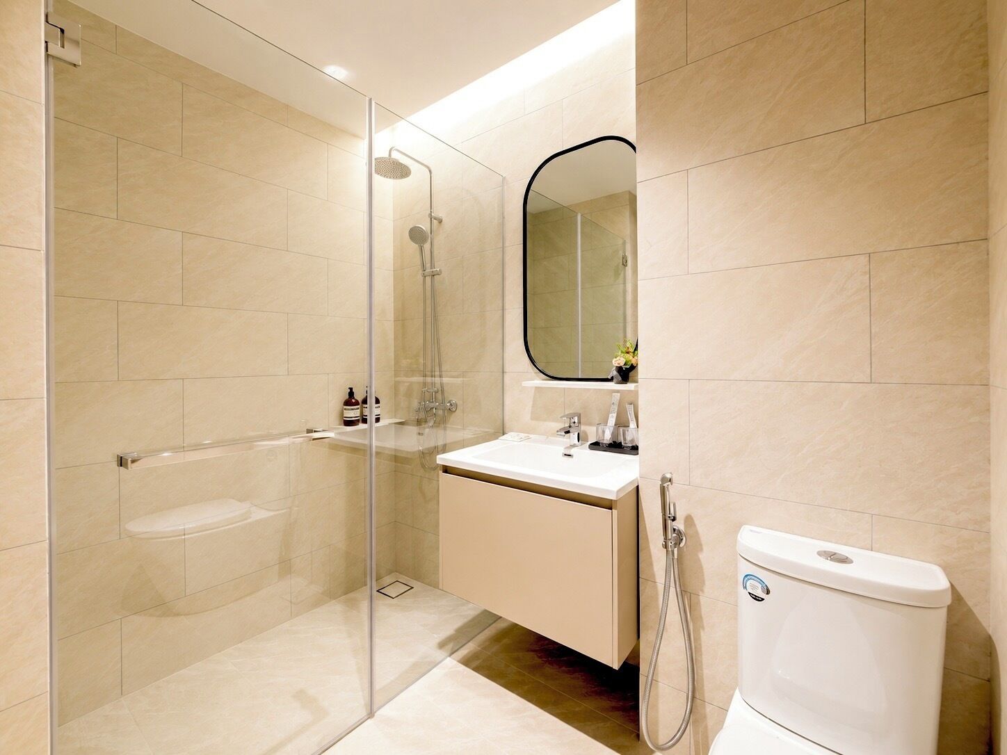 A modern bathroom with a glass-enclosed shower, a white sink, and a toilet.