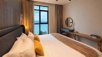 A hotel room with a bed, a desk, a chair, a large window, and a ceiling fan.