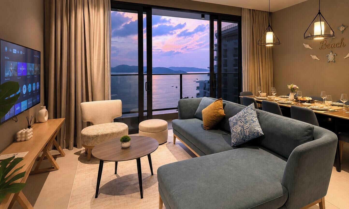 A modern living room with a sofa, armchair, dining table, and a TV.