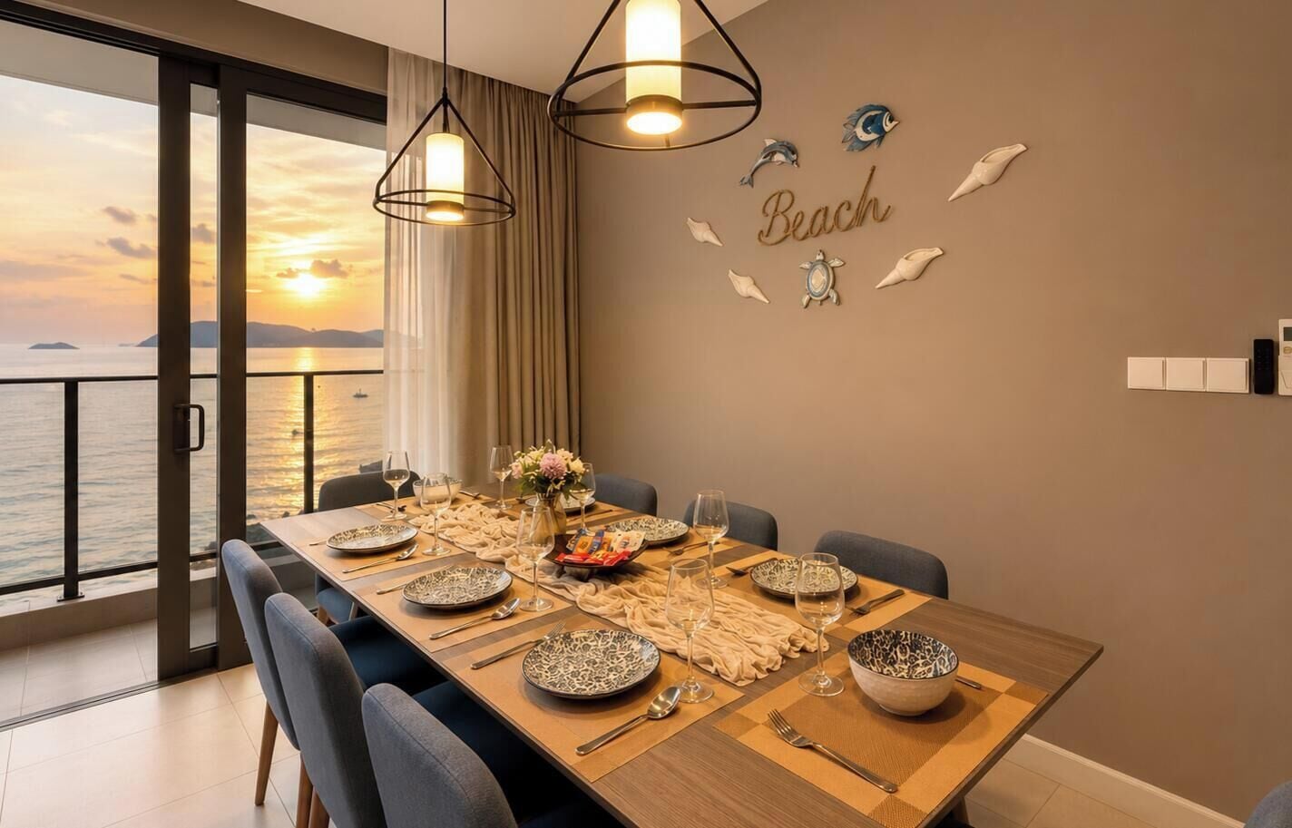 A dining area with a view of the sea, a table set for six, and decorative wall art.