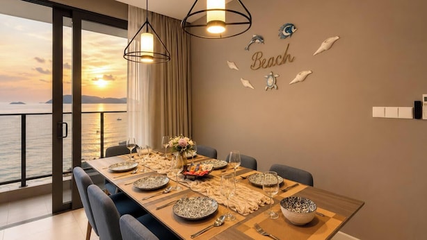 Un comedor con vista al mar, una mesa preparada para seis personas y decoración mural.