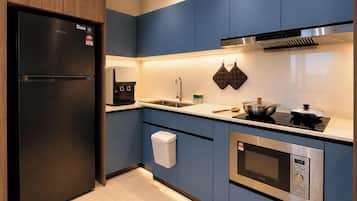A modern kitchen with a built-in refrigerator, coffee machine, microwave, and stove.