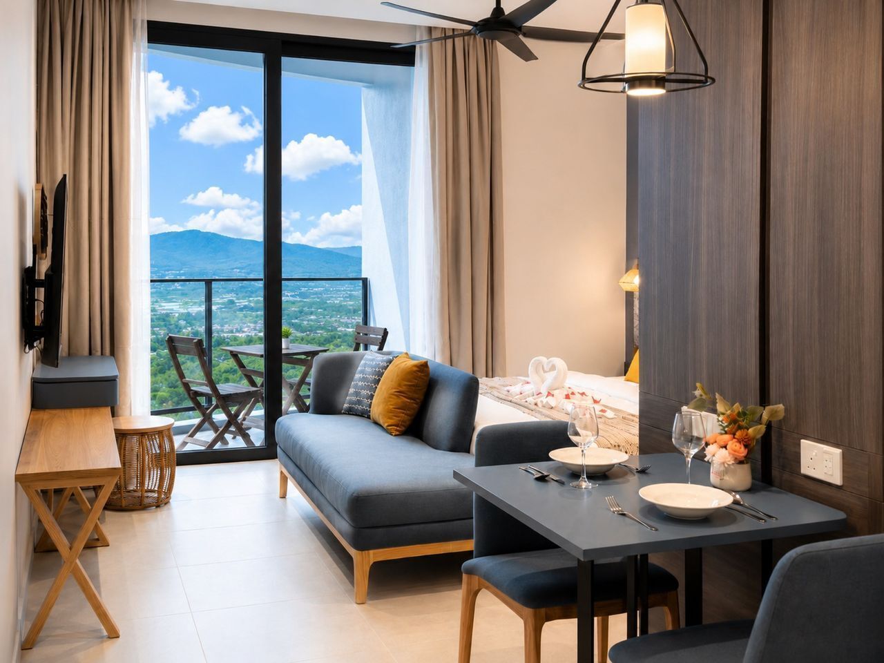 A modern hotel room with a balcony, a sofa, a dining table, and a TV.