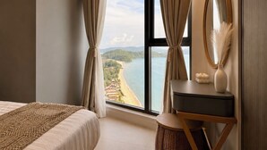 Un dormitorio con un ventanal grande, una cama, una mesita de noche, un espejo y vista a una playa.