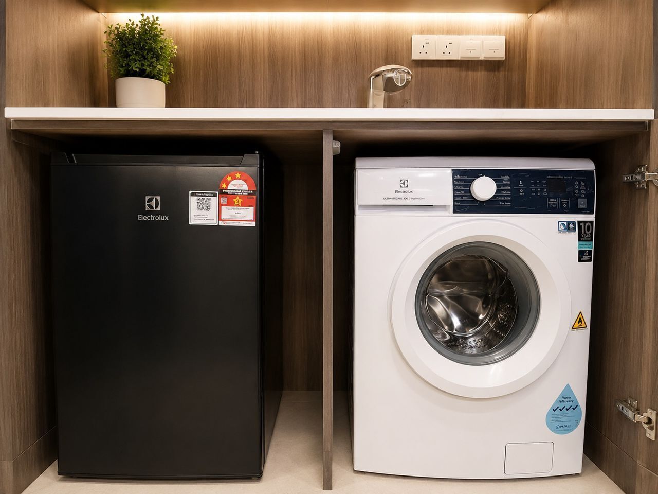 A compact laundry area with a black Electrolux refrigerator and a white washing machine.