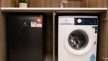 A compact laundry area with a black Electrolux refrigerator and a white washing machine.