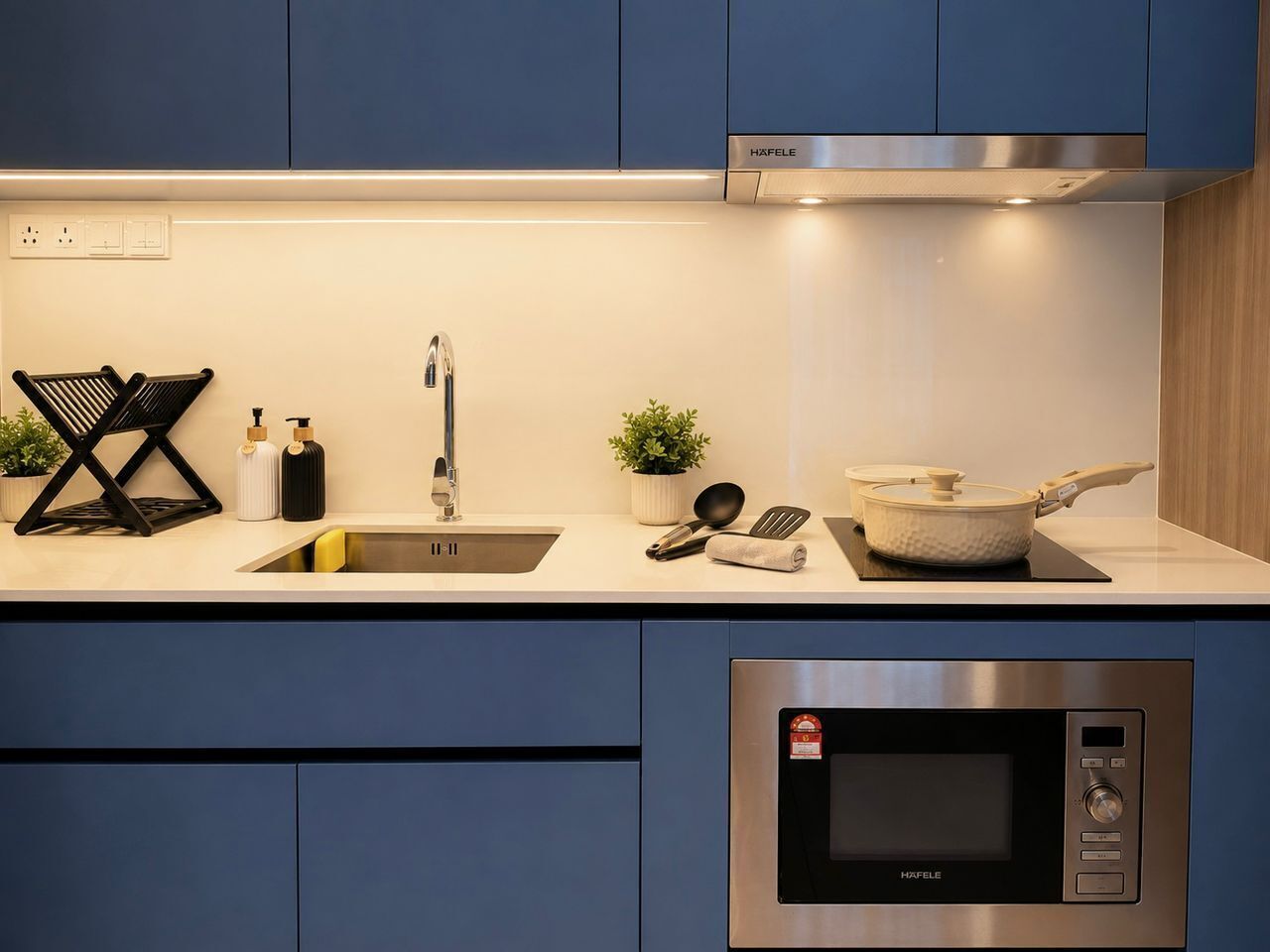 A modern kitchen with a stainless steel microwave, a sink, and a stove.