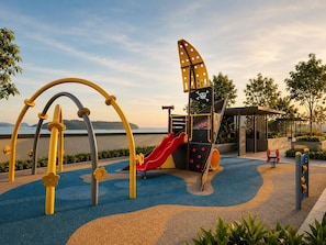 Un parque infantil con toboganes y estructuras para escalar cerca del agua.