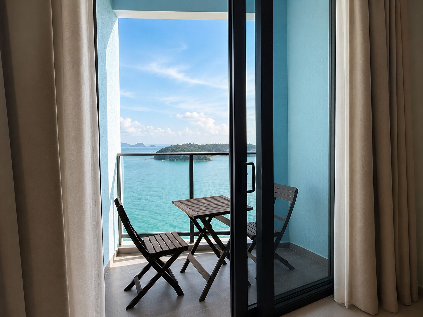 Uma varanda com mesa e duas cadeiras, com vista para a água e uma ilha ao longe.