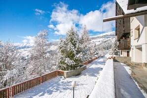 Schneebedeckte Landschaft mit einem Holzhaus und einem schneebedeckten Baum im Vordergrund.