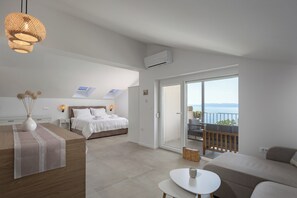 Ein modernes Hotelzimmer mit Bett, einer Couch, einem Balkon mit Blick und einem Essbereich.